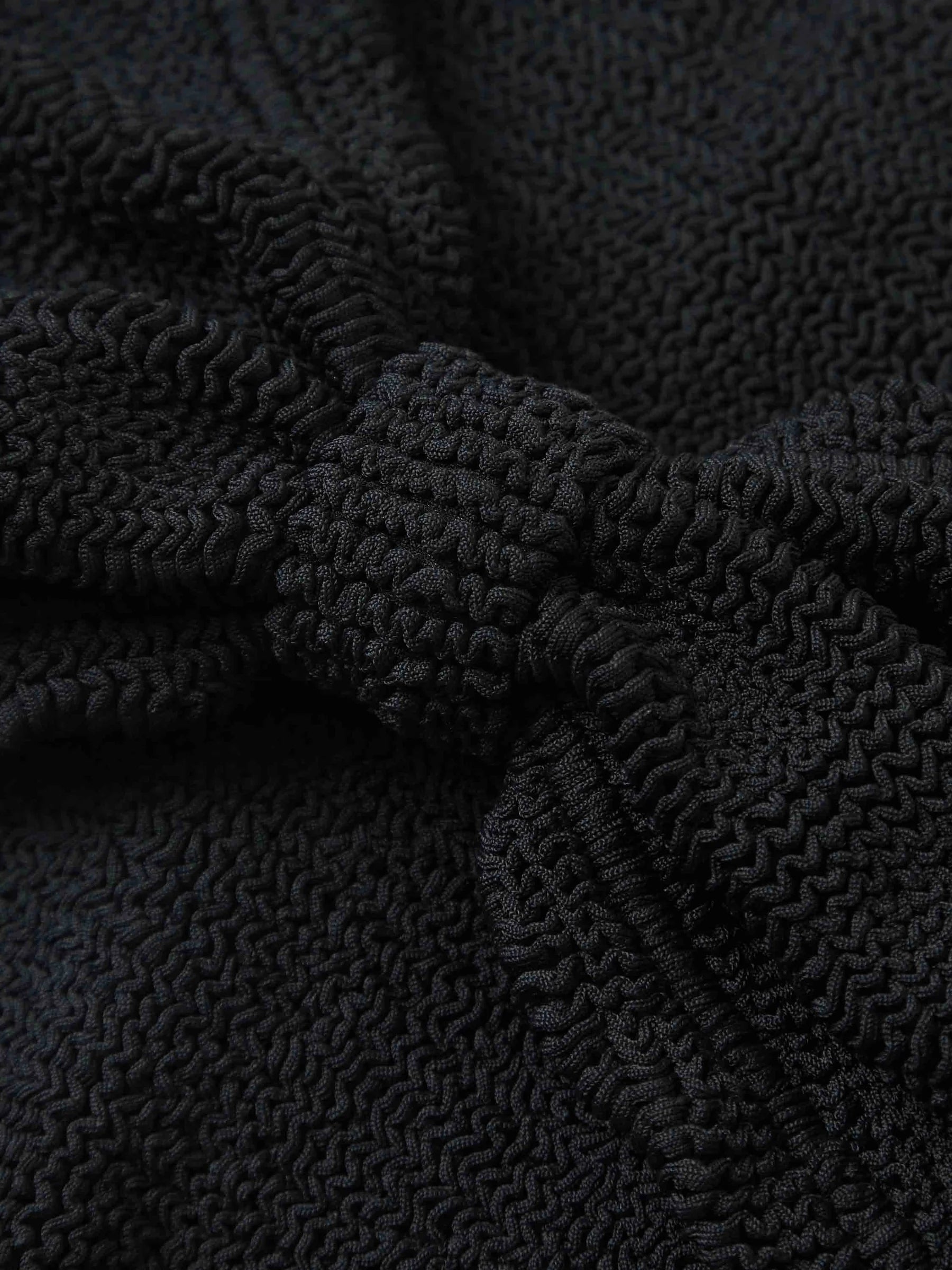 Close-up of black textured crinkle fabric with a knotted section in the center, displaying detailed wavy and raised patterns—ideal for the Hunza G Jean Bikini, featuring a one size fits all design.