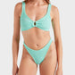 A woman wearing the Hunza G Julia Bikini, featuring a textured mint green, ocean-inspired design with pearly hoop detail on the top and high-cut bottoms, stands against a plain background.