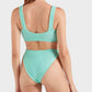 A woman with long hair models the Julia Bikini by Hunza G, featuring an ocean-inspired light blue textured design, shown from the back against a plain light background.