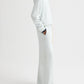 A person wearing a light-colored TWP PJ Pant, standing sideways with hands in pockets against a plain white background.
