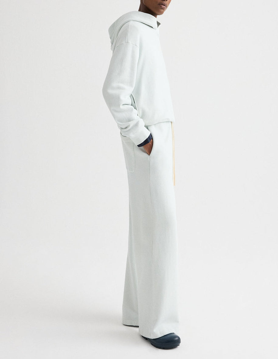 A person wearing a light-colored TWP PJ Pant, standing sideways with hands in pockets against a plain white background.