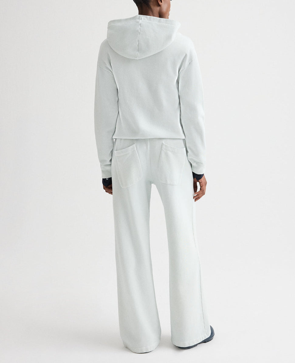 A person wearing the TWP Hoodie in light gray french terry with matching wide-leg pants stands with their back to the camera against a plain white background.