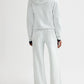 A person stands facing away, wearing TWP's light-colored French terry hooded sweatshirt and matching PJ Pant, set against a plain white background.
