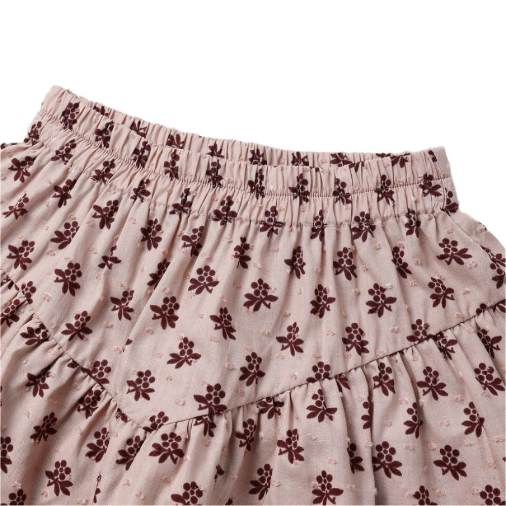 Close-up of the Girls' Tiered Mini Skirt by Rylee & Cru, featuring an elastic waistband, built-in shorts, and a small brown floral pattern on pink fabric.