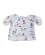The Puppy Patch Novelty Hat by Kissy Kissy is a white baby hat made from soft Pima cotton, featuring floppy ears and a playful puppy patch print with cartoon dogs, bones, and bowls in blue, gray, red, and yellow.