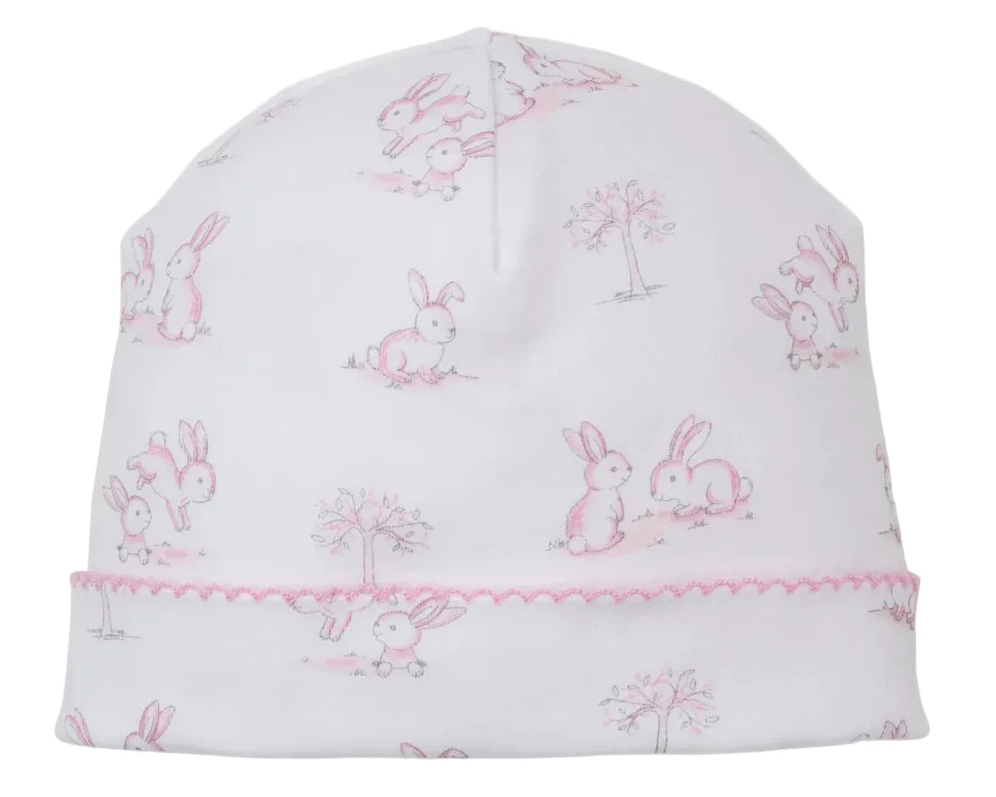 The Kissy Kissy Springtime Bunny Fun Hat is a white Pima cotton baby hat with pink embroidered trim, featuring a delightful light pink and gray bunny and tree print.