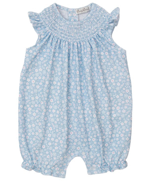 The Kissy Kissy Baby Girls' Fall in Bloom Smocked Sleeveless Playsuit features a white floral pattern, ruffled shoulders, smocked neckline, and elastic leg openings.