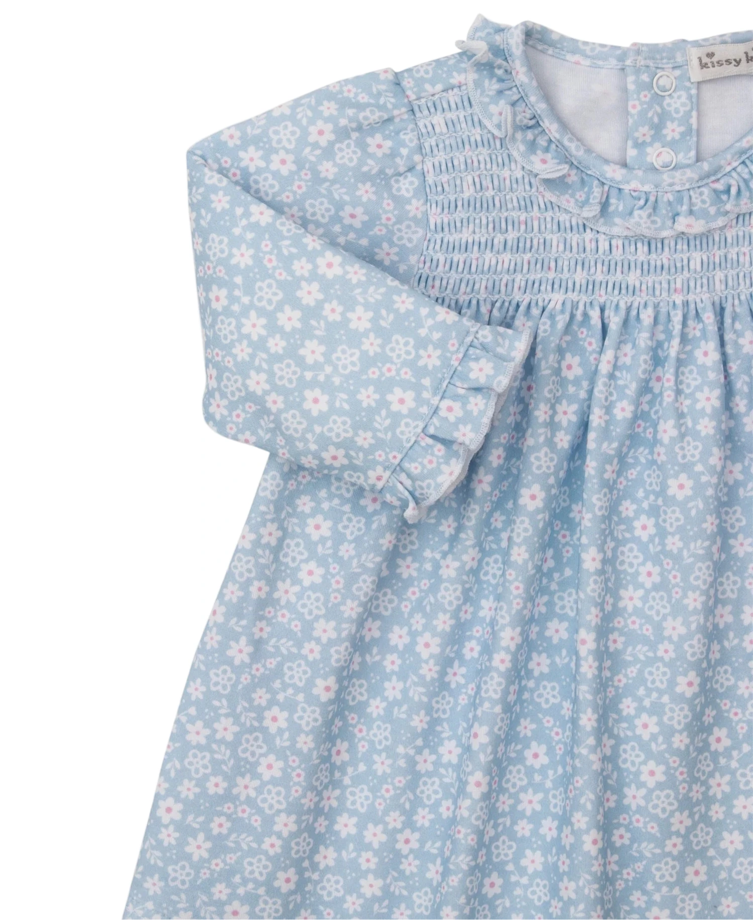 The Kissy Kissy Baby Girls' Fall in Bloom Printed Smocked Dress Set is a soft Pima cotton long-sleeve dress with white and pink floral print, smocked chest, ruffled collar, and button accents at the neckline.