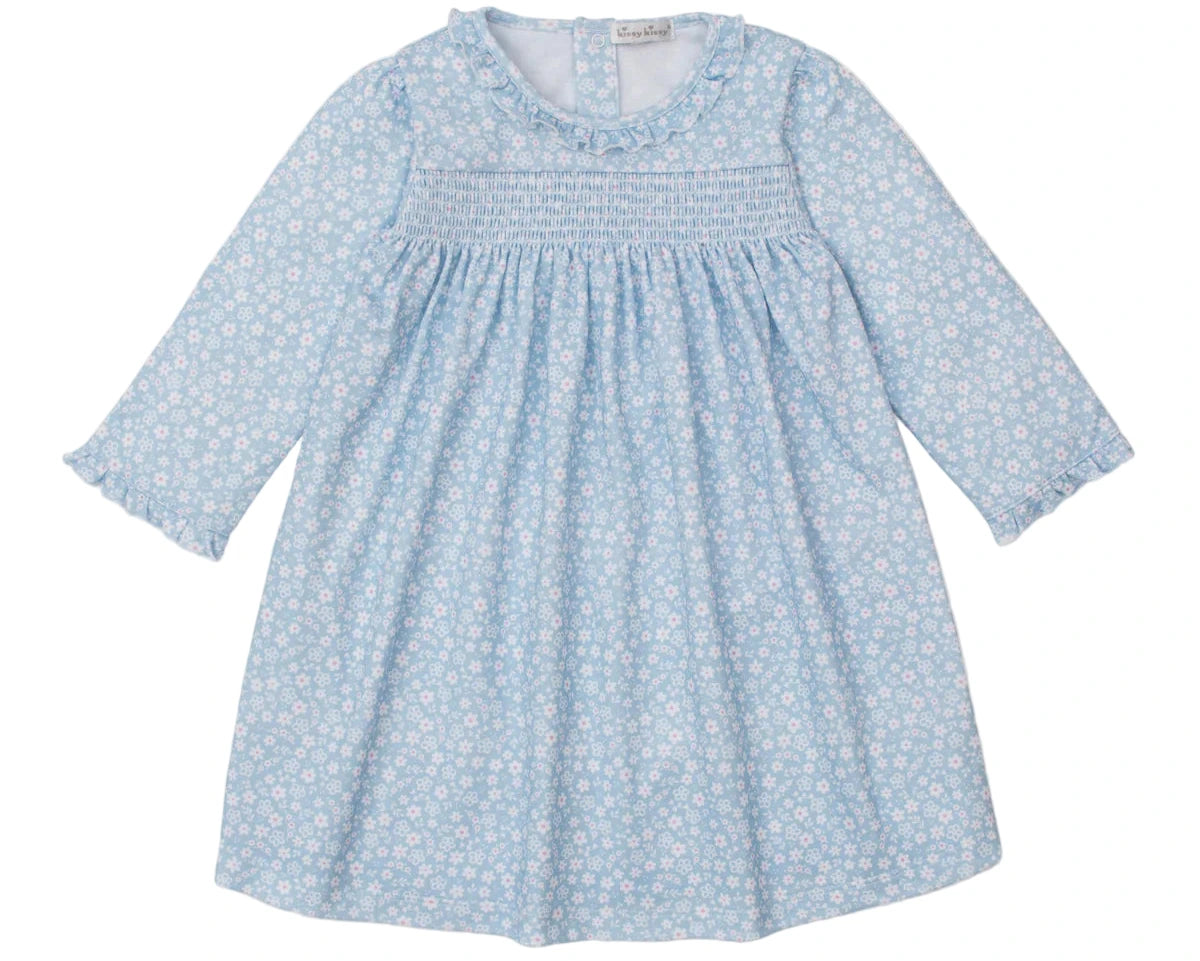 The Kissy Kissy Girls' Fall in Bloom Printed Smocked Dress features long sleeves, a white floral print on light blue, a gathered bodice, ruffled collar, elastic cuffs, and soft Pima cotton for toddler comfort.
