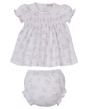 The Kissy Kissy Baby Girls' Springtime Bunny Fun Smocked Dress Set features a white Pima cotton dress with pink bunny print, ruffled edges, and a matching diaper cover—crafted for softness and comfort.