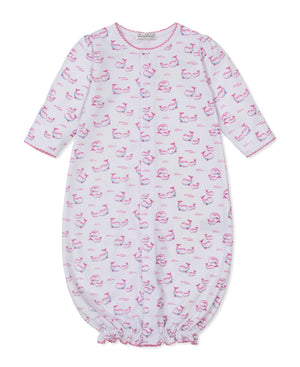 Kissy Kissy Baby Whale Pods Convertible Gown in white Pima cotton, adorned with a delightful pink whale pods print, features long sleeves, pink trim on the cuffs and collar, and an elastic bottom. The sleepwear garment is shown laid flat on a white background.
