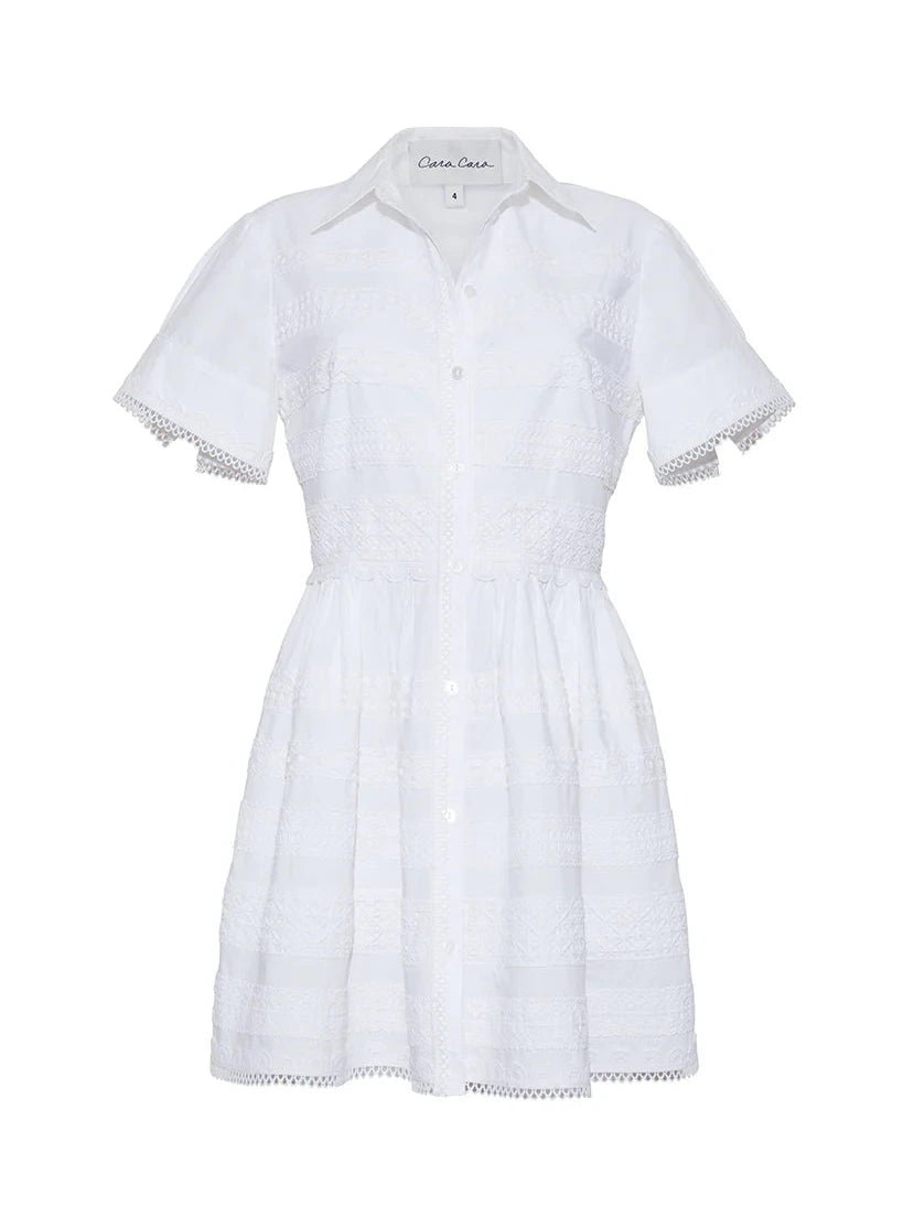 The Kai Mini Dress by Cara Cara is a white short-sleeve, button-down dress with a collared neckline and delicate lace insets on the bodice, skirt, and sleeves for an effortlessly charming style.