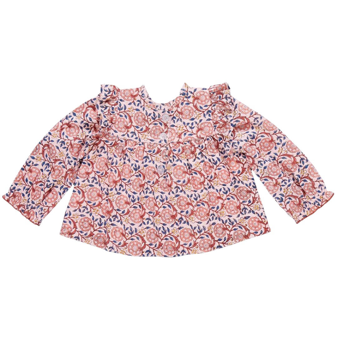 The Pink Chicken Girls' Kalani Top is a long-sleeve blouse featuring the charming Pink Blossom Block Print with pink and red floral patterns on a white background, complete with ruffled shoulders and a round neckline.