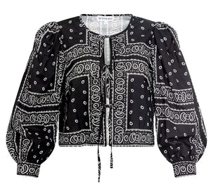 The Katie Top by Hunter Bell NYC is a black bandana-style top with white paisley and geometric prints, balloon sleeves, a round neckline, and a stylish tie-front closure.