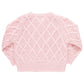 This image shows the Pink Chicken Girls' Katrina Sweater, a long-sleeve knit sweater in pink with a diamond pattern design. The sweater features glitter button closures and has ribbed hems, cuffs, and neckline.