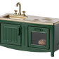 A miniature dark green Maileg kitchen for mice, featuring a brass faucet, two stove burners, and an oven door with a baked potato inside—perfect for the Mouse family kitchen.