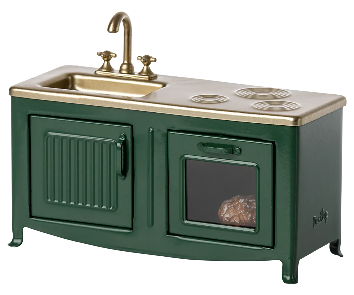 A miniature dark green Maileg kitchen for mice, featuring a brass faucet, two stove burners, and an oven door with a baked potato inside—perfect for the Mouse family kitchen.