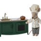 A Maileg stuffed mouse dressed as a chef stands proudly in the Mouse family kitchen beside the Maileg Kitchen for Mice in dark green, complete with a sink, stovetop, and a freshly baked pie.