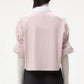 A person is shown from the back wearing the TWP Next Ex Classic Barre Striped Cotton Shirt in pink and white over a long-sleeve white top, paired with a black skirt.