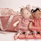 Two Poppy Baby Dolls by Mon Ami, dressed in pink cuddle-perfect fabric, sit together next to a floral-lined carry bag.