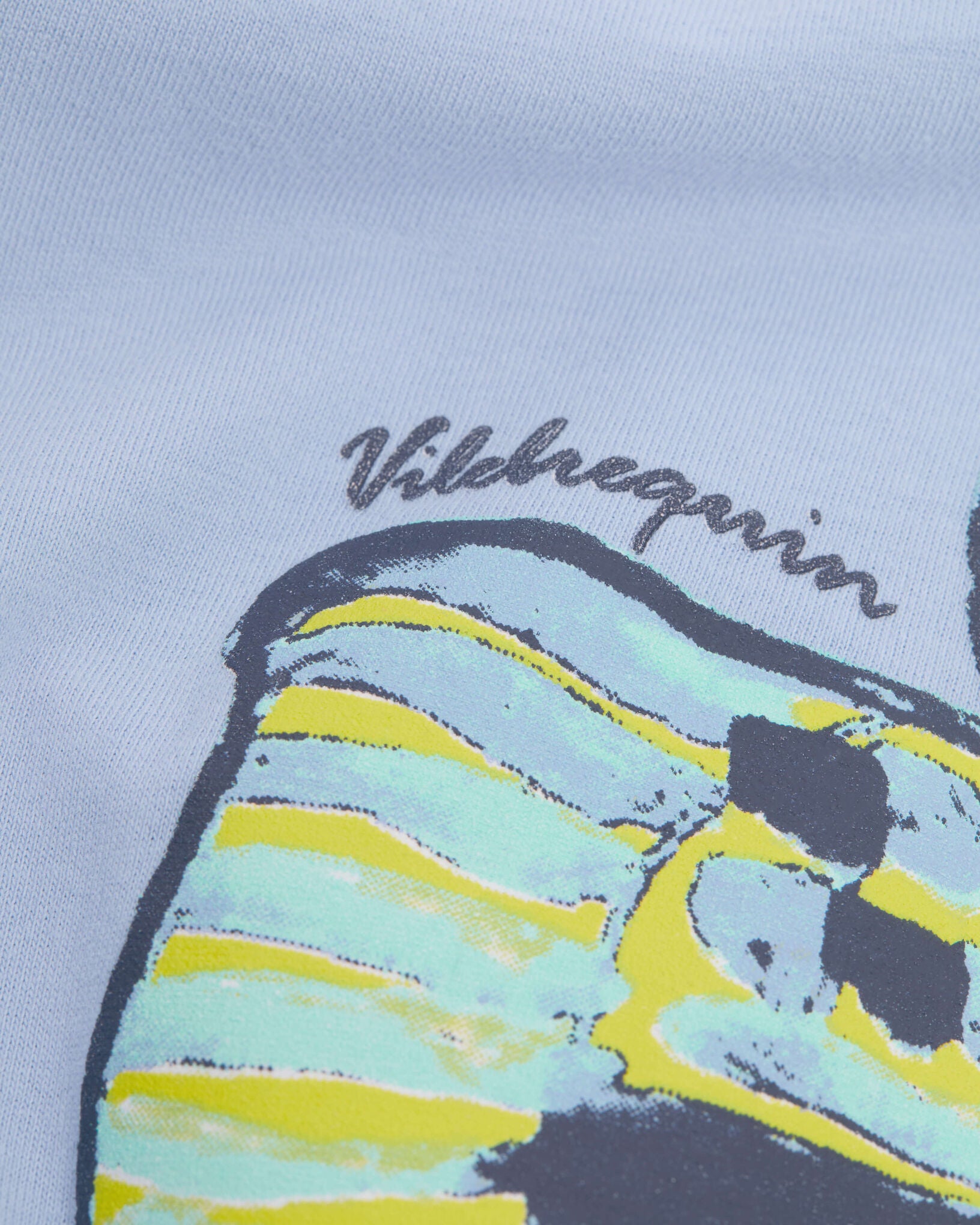 Close-up of Vilebrequin's Boys' Fish Tee: oversized organic cotton, relaxed cut, with a puff-ink print of a striped sphinx head beneath "Vilebrequin.