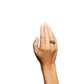 A hand with light skin is raised against a white background, highlighting the chunky gold Sofie Ring by Lie Studio on the middle finger for a bold statement.