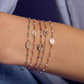 A wrist wearing four Gigi Clozeau Madone Charm Bracelet 6.7" pieces, each adorned with oval medallion charms and small colored beads in green, purple, pink, and white.