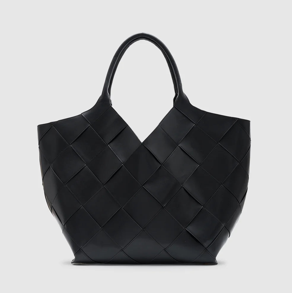 The Lili Braided Leather Tote by Anine Bing, a spacious black leather bag featuring a braided finish and dual handles, is showcased against a plain light gray background.