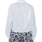 A person is seen from the back wearing the Callas Milano Lille Top, a loose white cotton poplin point collar shirt, paired with black-and-white floral patterned pants against a plain background.