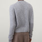 Model wearing the Lisa Yang Marionette Cardigan in light gray, paired with brown pants, shown from the back against a plain light background.
