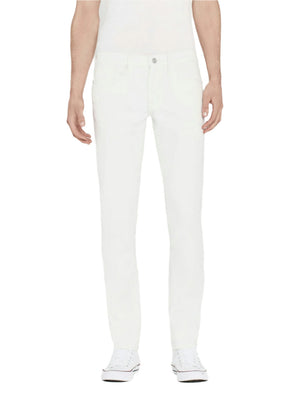 Someone wearing Frame's L'Homme Slim jeans, a white shirt, and white sneakers stands facing forward against a plain background.