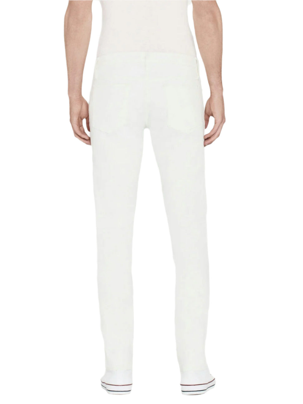 A person wearing Frame L'Homme Slim mid-rise, straight leg white jeans and white socks stands facing away from the camera, displaying the back of the jeans.