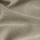 Close-up view of L'Homme Slim Brushed Twill fabric by Frame, featuring a beige hue with vertical ridges similar to comfort-stretch denim, and a slightly wrinkled texture.