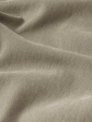 Close-up view of L'Homme Slim Brushed Twill fabric by Frame, featuring a beige hue with vertical ridges similar to comfort-stretch denim, and a slightly wrinkled texture.