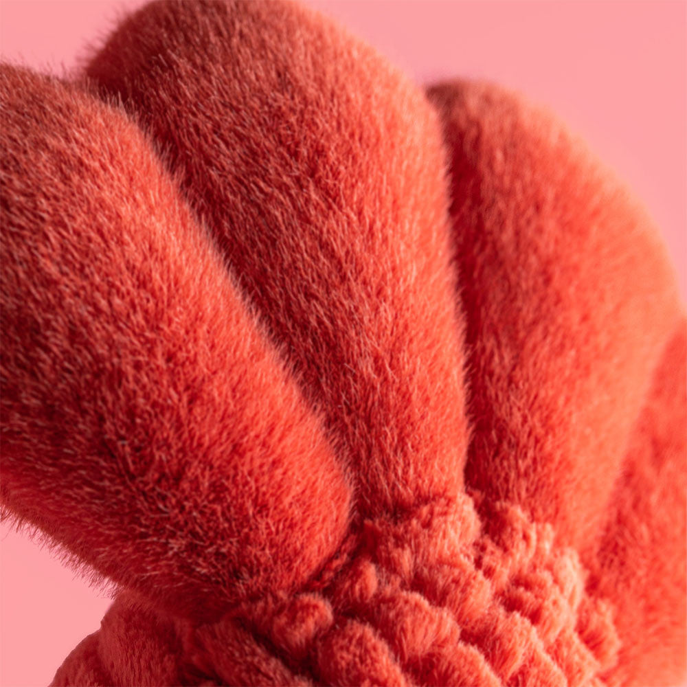 Close-up of the Jellycat Larry Lobster Sailor Outfit, featuring soft, plush red fabric with textured, rounded sections—set against a solid pink background—ready for playful nautical adventures.
