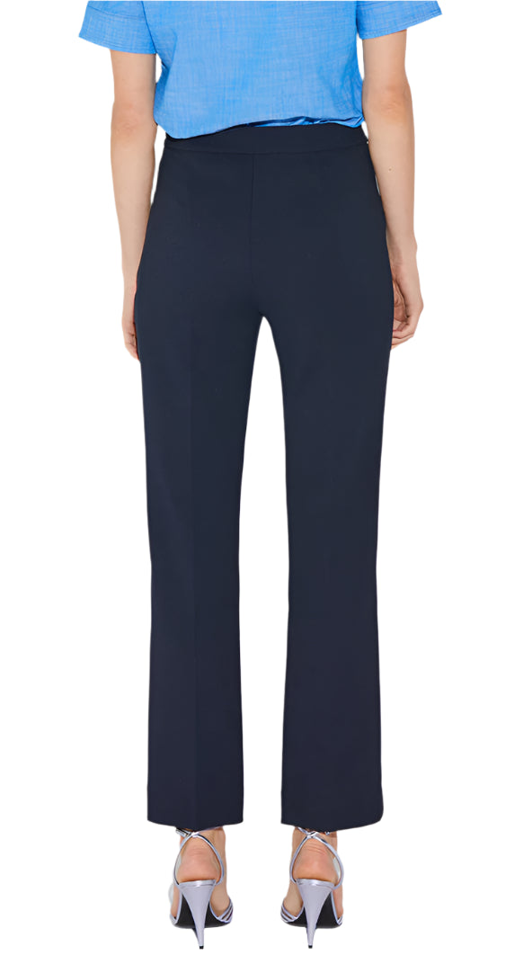 Rear view of a person in Callas Milano's high-rise Lola Pant and a blue shirt, standing with silver heels visible.