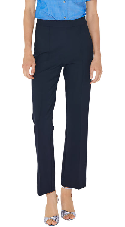 A person is wearing a blue button-up shirt, Callas Milano's Lola Pant in black, and silver open-toe heels, standing against a plain white background.