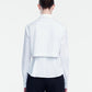 A person stands with their back to the camera against a plain background, wearing the Lela Rose Cotton Poplin Layered Shirt paired with black pants and a white relaxed fit cropped jacket.
