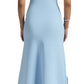 A woman in a Lela Rose sleeveless light blue knit midi dress stands facing away, featuring side ruffles on the full-length skirt. She completes the look with white heels and a silver bracelet.
