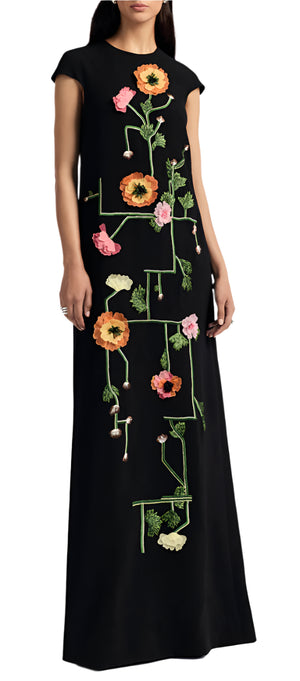 A person wears the Augusta Embroidered Gown by Lela Rose, showcasing vibrant tulip fields in orange, pink, and green against a long black dress. The gown's silhouette beautifully highlights its exquisite floral embroidery.