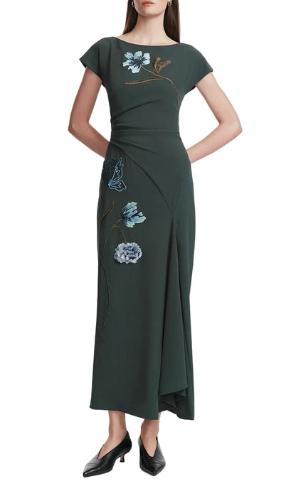 A woman in the Lela Rose Floral Fluid Crepe Cascade Dress with blue floral cord embroidery and black low heels stands against a plain white background.