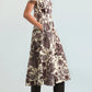A woman wearing the Sawyer Dress by Cara Cara—a short-sleeved, floral-patterned poplin midi dress with pockets—paired with knee-high black boots, stands against a plain light background.