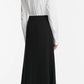A woman faces away in a white long-sleeve shirt tucked into the Lela Rose Drop Flower Ruched Skirt, featuring an elegant high-waisted A-line silhouette, paired with black heels, set against a plain white background.