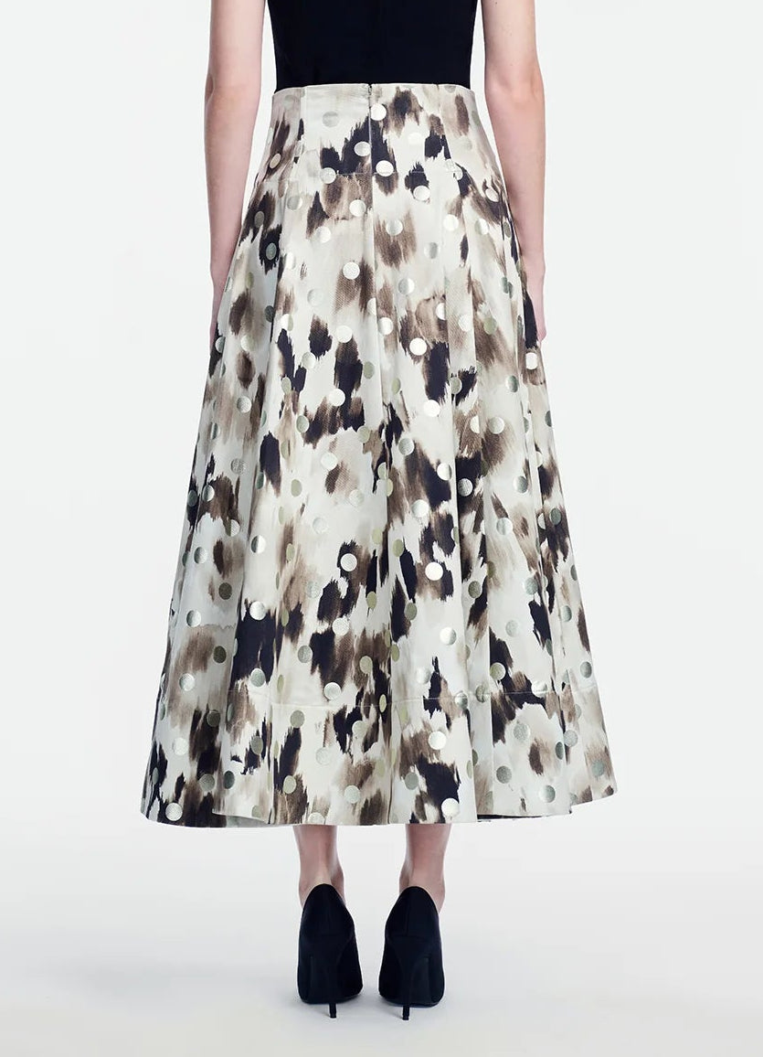 A person wearing a black top and a high-waisted, ankle-length Lela Rose Ikat Polka Parker Skirt, featuring a beige and black abstract pattern, seen from the back, paired with black heels.