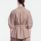 A person stands with their back to the camera, wearing the Lela Rose Melange Crepe Camp Shirt and matching pants, both crafted from textured fabric in a light brown hue that highlights a classic silhouette.
