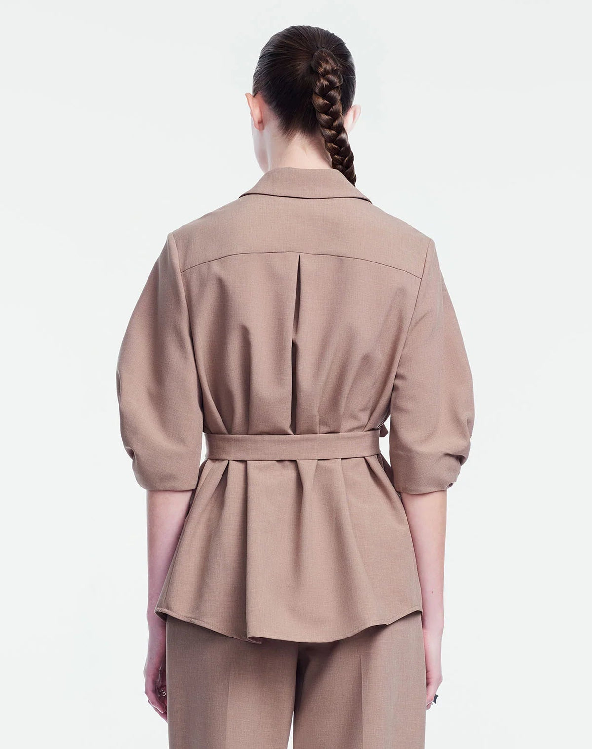 A person stands with their back to the camera, wearing the Lela Rose Melange Crepe Camp Shirt and matching pants, both crafted from textured fabric in a light brown hue that highlights a classic silhouette.