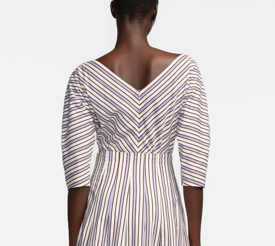 A person is shown from the back wearing the Lela Rose Striped Cotton Dolman Sleeve Top in cream, featuring diagonal and vertical stripes, a V-shaped neckline, and three-quarter dolman sleeves for a stylish yet professional look.
