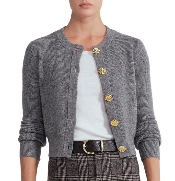 Outfitted in the Cara Cara Ellery Cardigan—a grey knit featuring gold floral buttons—layered over a white shirt, paired with plaid trousers and finished with a black belt with a gold buckle, this classic ensemble is the perfect wardrobe staple.