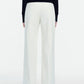 A person stands facing away against a plain white background, wearing a black long-sleeve top paired with the Lela Rose Stretch Cotton Molly Pant—high-waisted, wide-leg white pants featuring a high-rise silhouette.