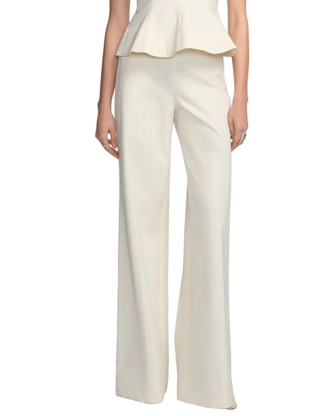 Model in Lela Rose Stretch Cotton Pant, featuring a tailored, high-rise waist in cream, paired with a matching peplum top; photographed from shoulders to feet against a white background.